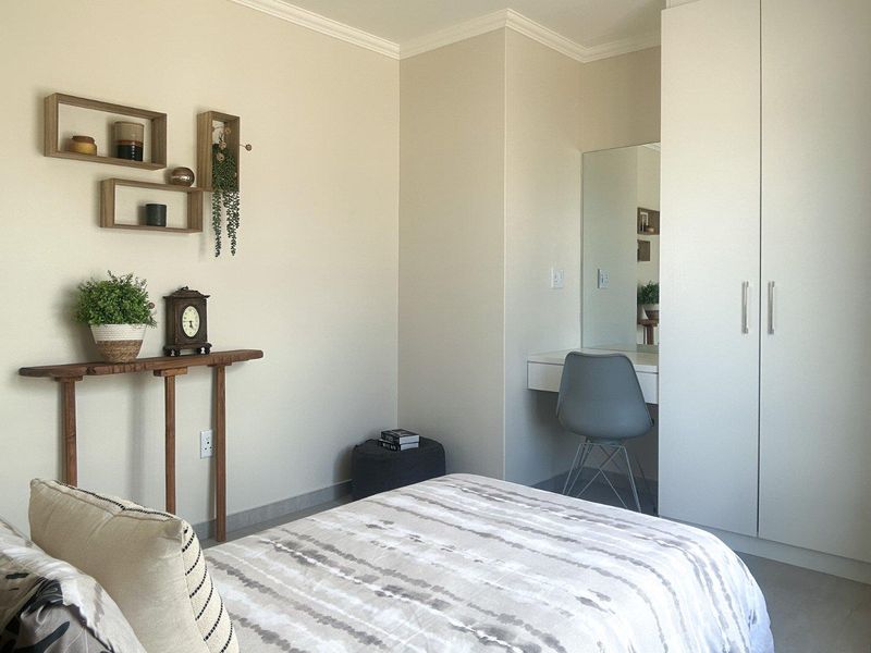 A well-maintained bedroom featuring a built-in wardrobe and a integrated vanity area with a mirror, finished with neutral walls and coving.