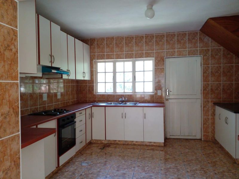 A functional kitchen featuring built-in cabinetry, a gas hob, oven, and double sink with tiled finishes throughout.