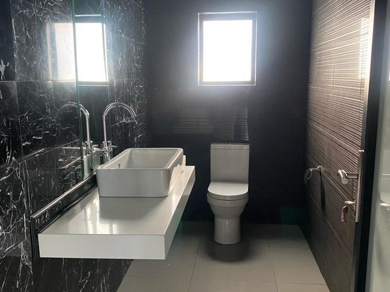 Modern bathroom featuring dark marble-effect wall tiles, a floating vanity with a vessel sink, and a minimalist toilet.