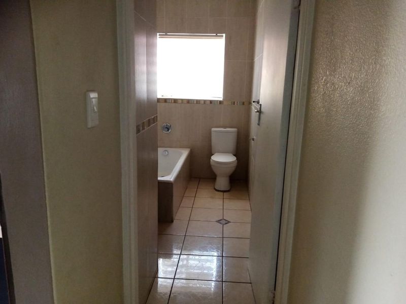 A functional bathroom featuring tiled walls and flooring, a built-in bathtub, and a standard toilet.