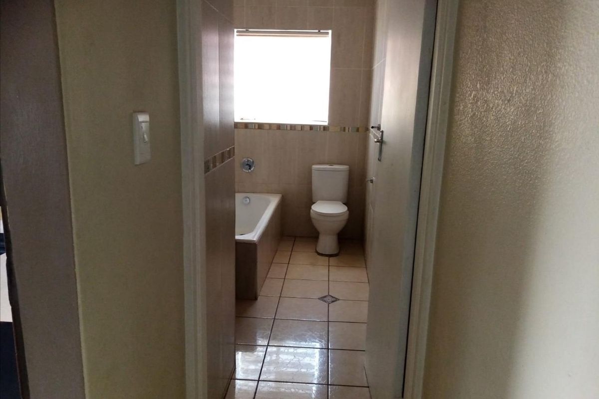 A functional bathroom featuring tiled walls and flooring, a built-in bathtub, and a standard toilet.
