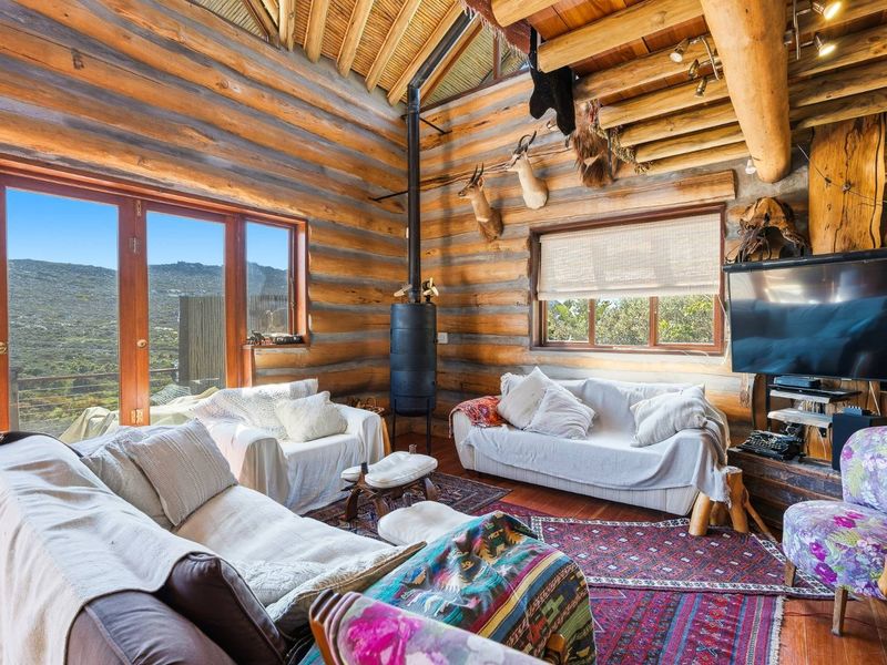 Rustic living room featuring exposed log walls, timber ceiling beams, a wood-burning stove, and large windows offering scenic mountain views.