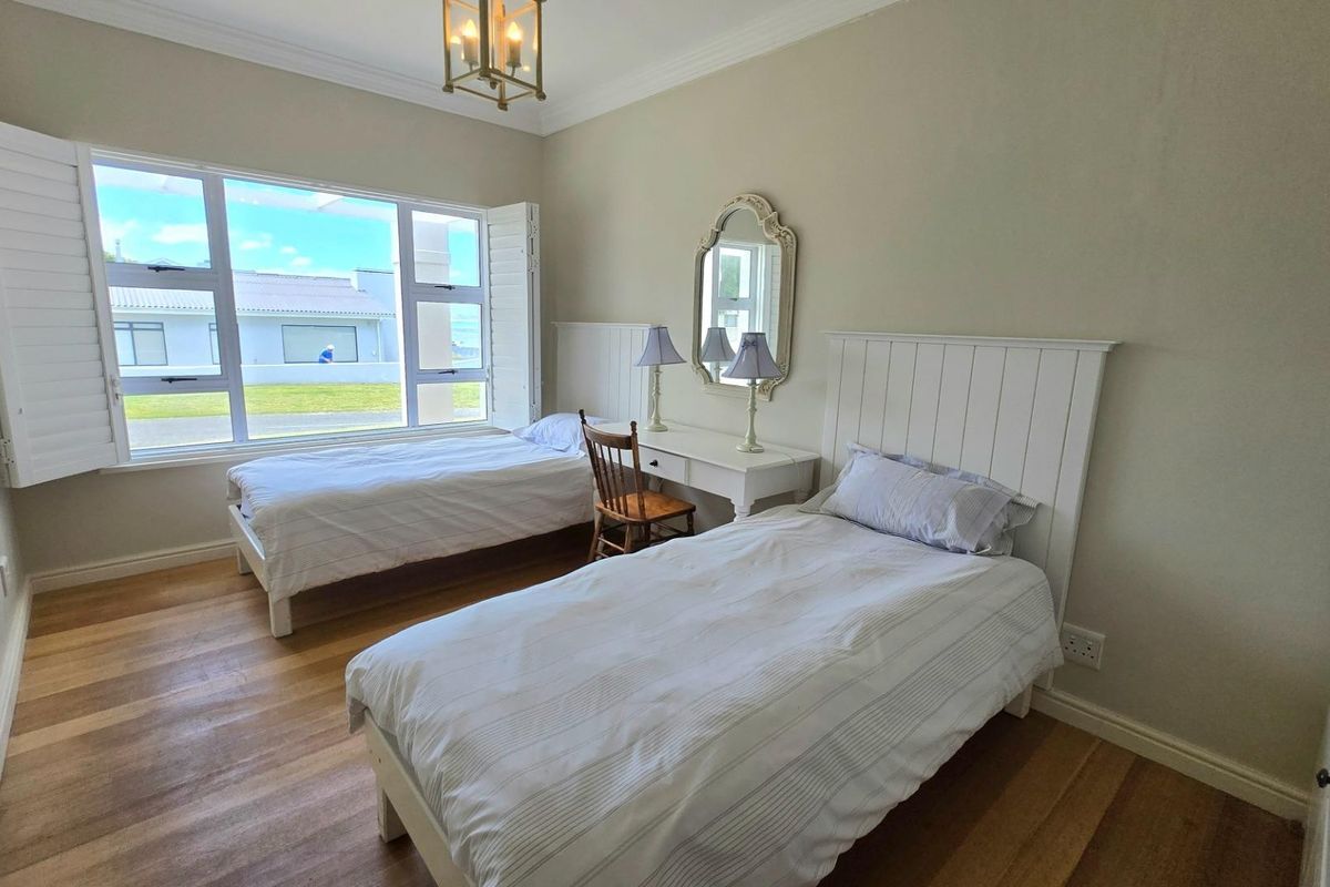 A bright bedroom featuring timber flooring, white plantation shutters, and crown molding, offering a clean and well-maintained living space.