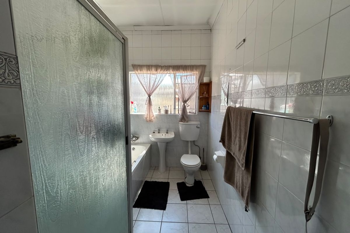 A functional bathroom featuring a bathtub, pedestal basin, toilet, and a separate shower enclosure with tiled finishes throughout.