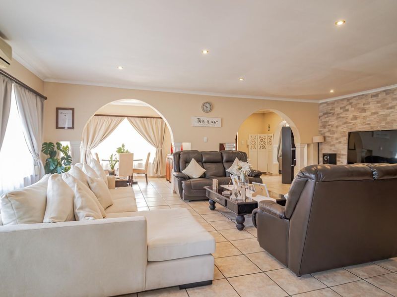 Spacious open-plan living area featuring tiled flooring, decorative archways, and a stone-cladding feature wall, creating a warm and inviting atmosphere.