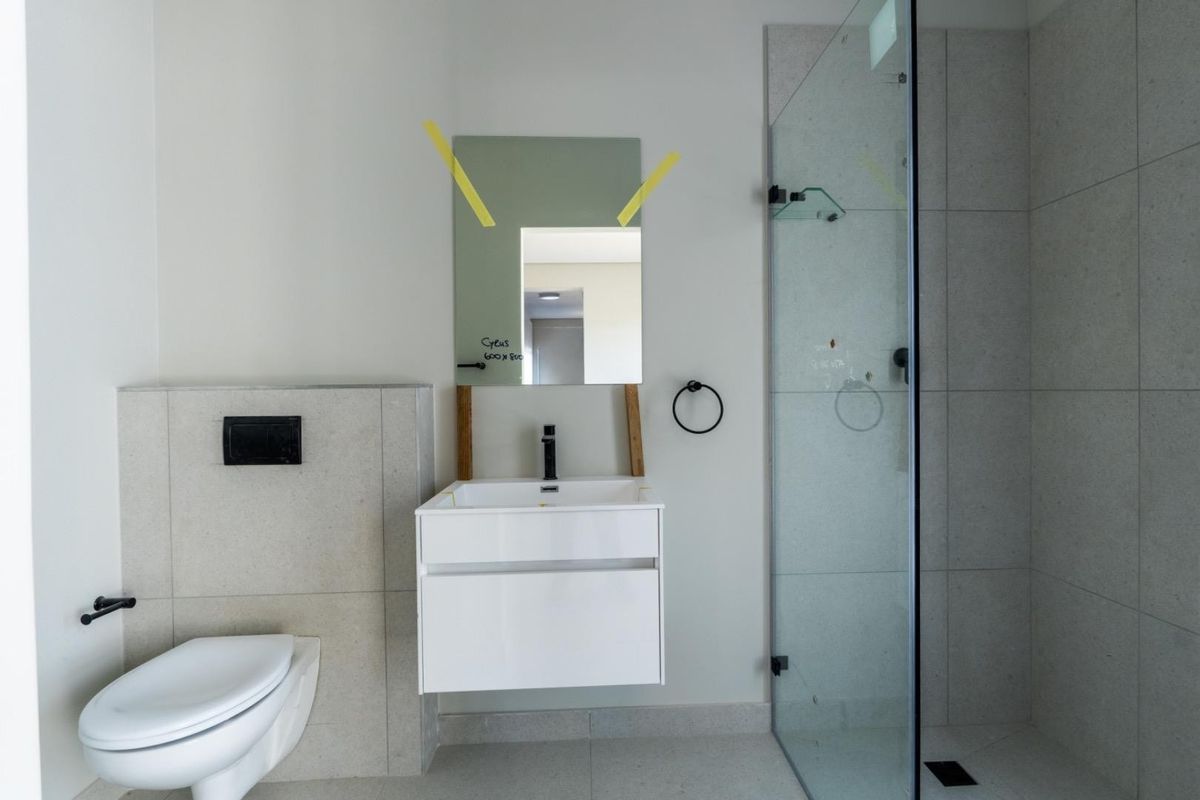 Modern bathroom featuring a wall-mounted vanity, a concealed cistern toilet, and a glass-enclosed walk-in shower with neutral tiling.