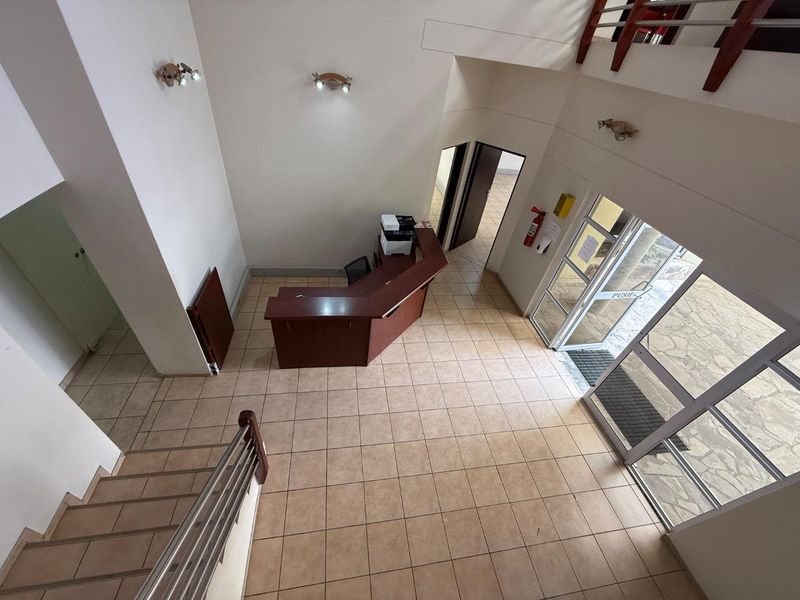 Spacious industrial entrance foyer featuring tiled flooring, a built-in reception desk, and a staircase leading to the upper level.