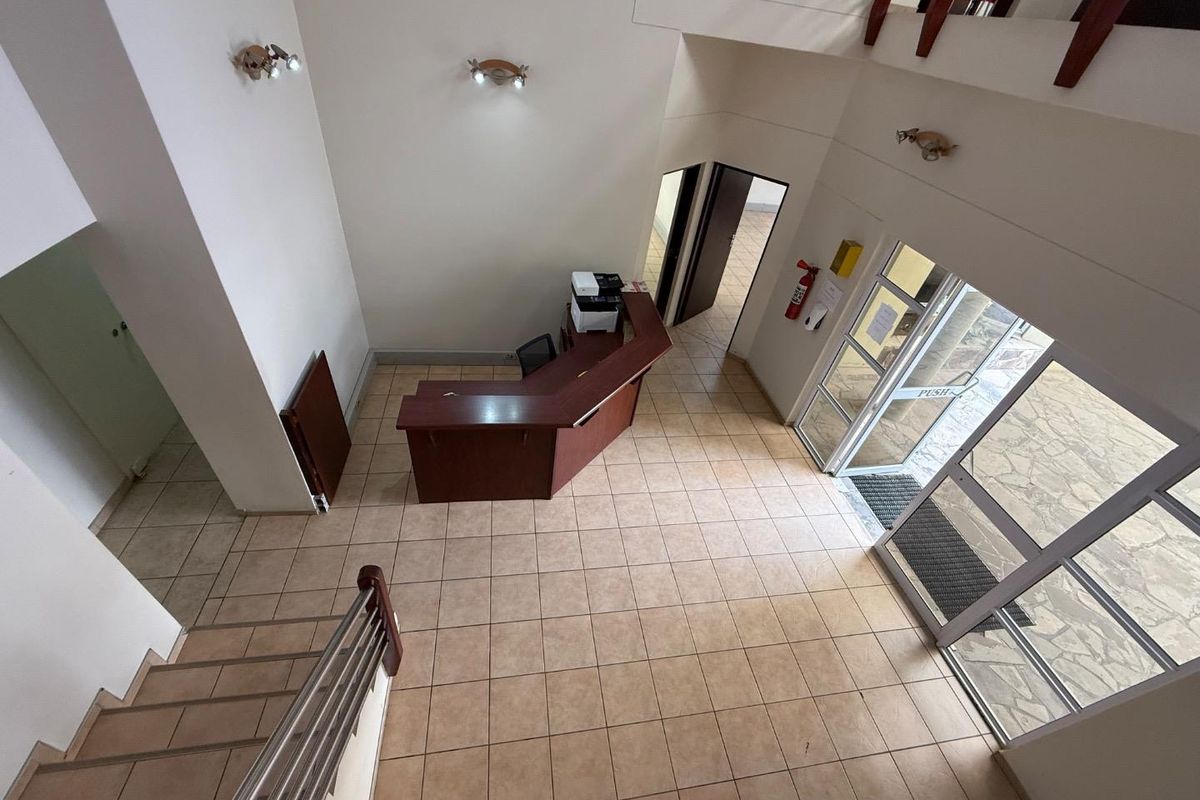 Spacious industrial entrance foyer featuring tiled flooring, a built-in reception desk, and a staircase leading to the upper level.