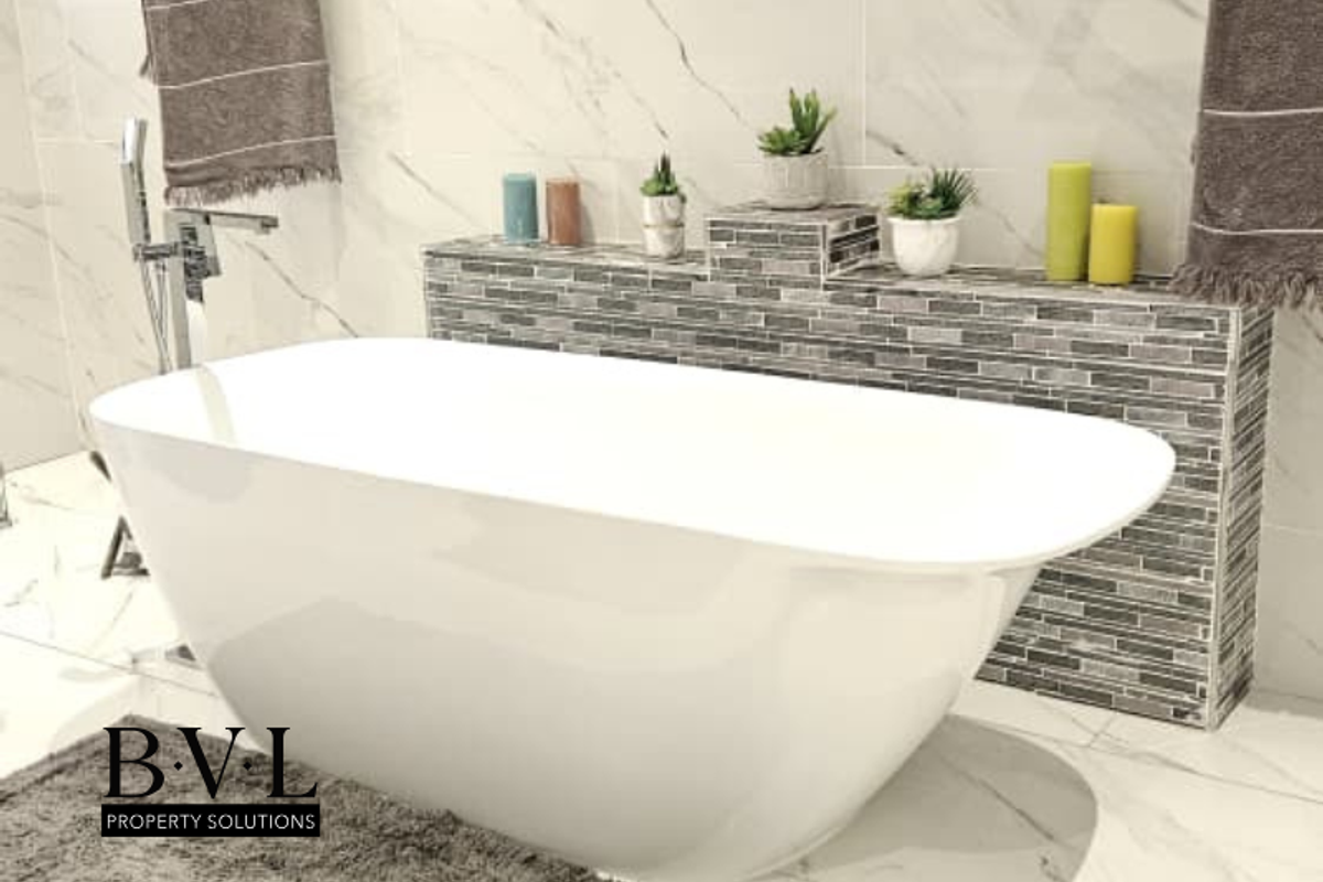 Modern bathroom featuring a sleek freestanding bathtub, marble-look wall tiles, and a decorative mosaic tiled feature wall with built-in shelving.