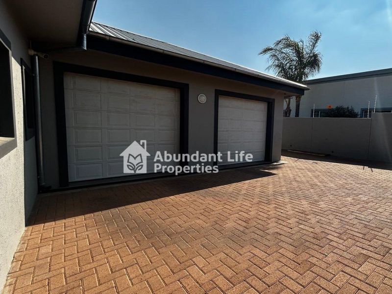 A well-maintained double garage with paved driveway access and secure perimeter walling.