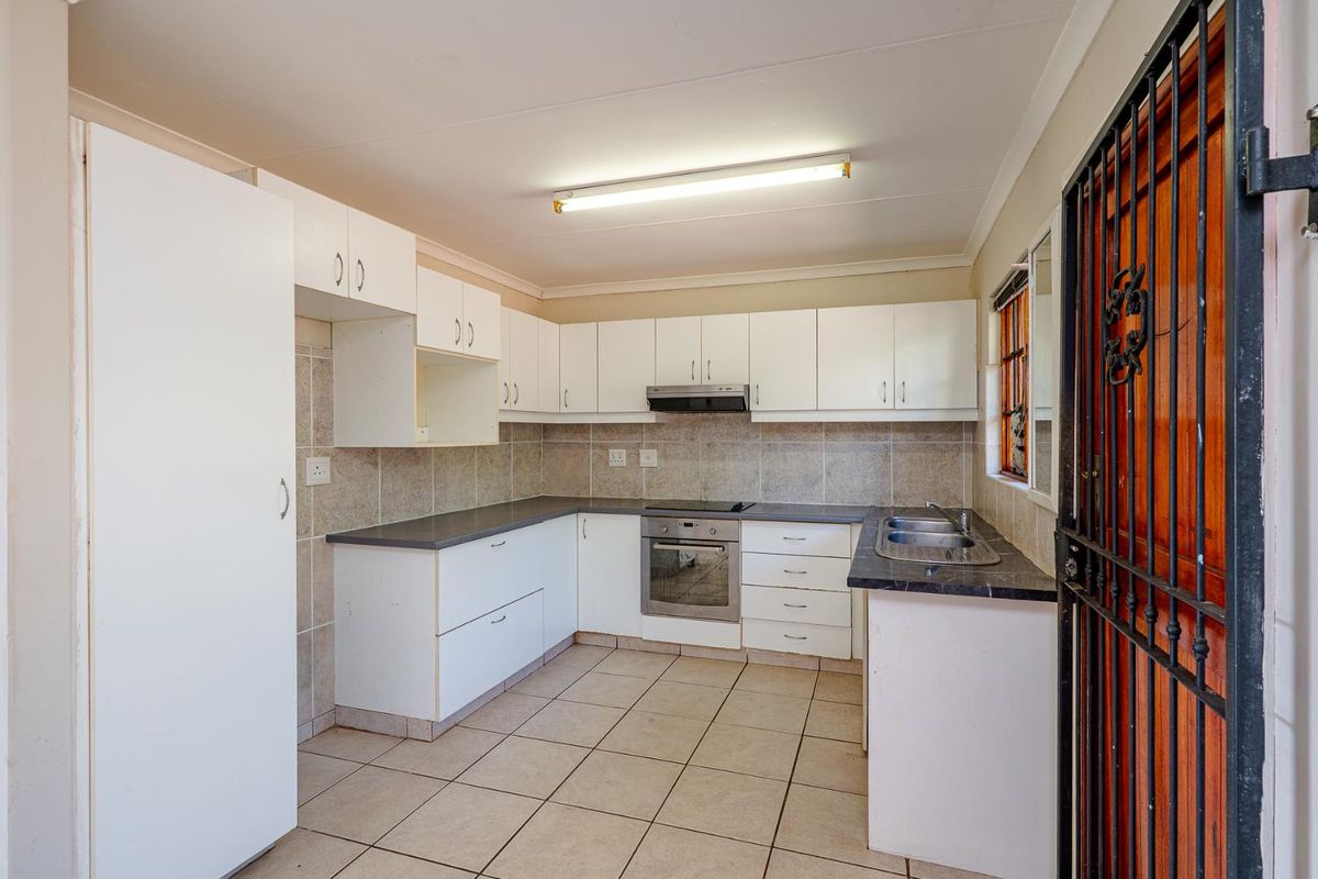 Functional kitchen featuring white cabinetry, tiled backsplash, built-in oven, hob, extractor fan, and double sink with tiled flooring.