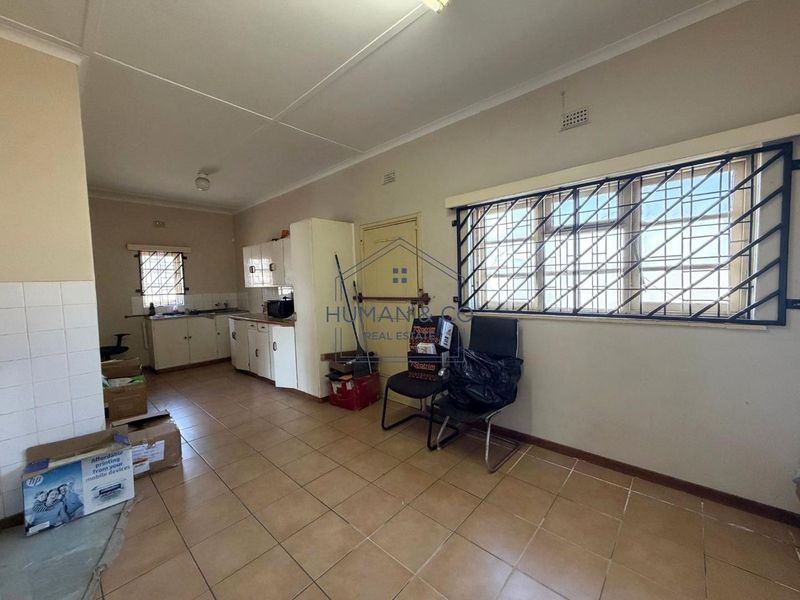 A functional kitchen space featuring tiled flooring, built-in cabinetry, and security bars on the windows, offering potential for modernization.