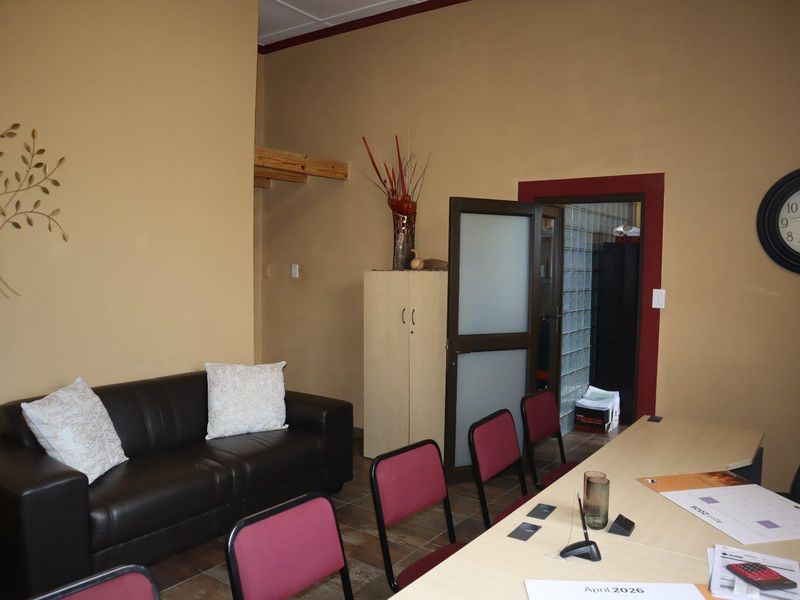 A functional office space featuring tiled flooring, a frosted glass door, and a glass block wall partition.