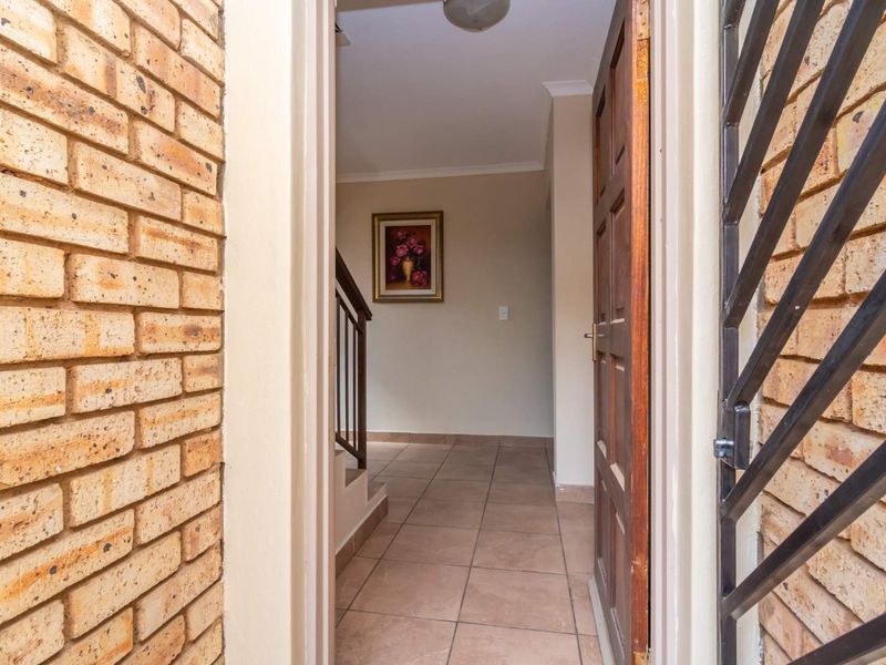 Entrance area featuring tiled flooring, exposed brick exterior wall, and a timber door leading into the home's interior staircase.