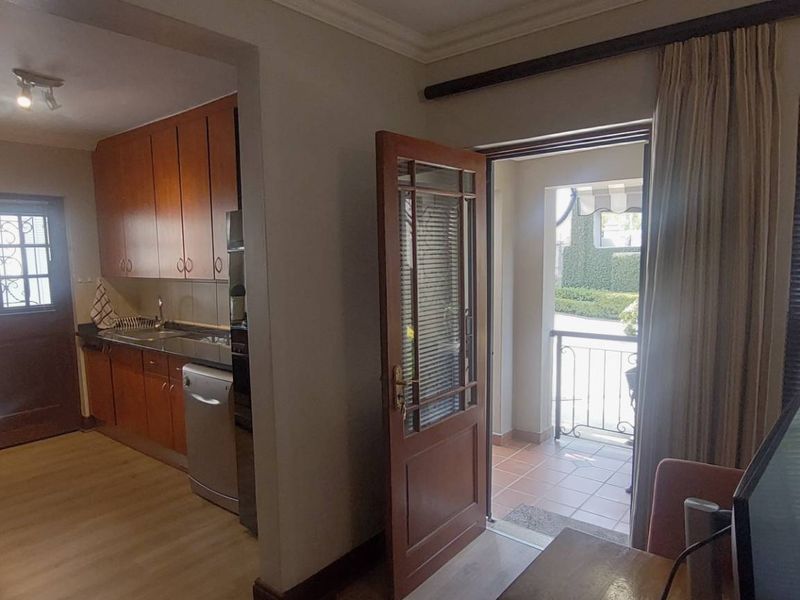 Open plan kitchen area featuring wooden cabinetry and direct access to a private patio through a timber door.
