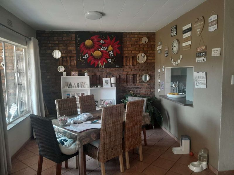 Dining room featuring an exposed brick wall, tiled flooring, and a convenient serving hatch connecting to the kitchen area.
