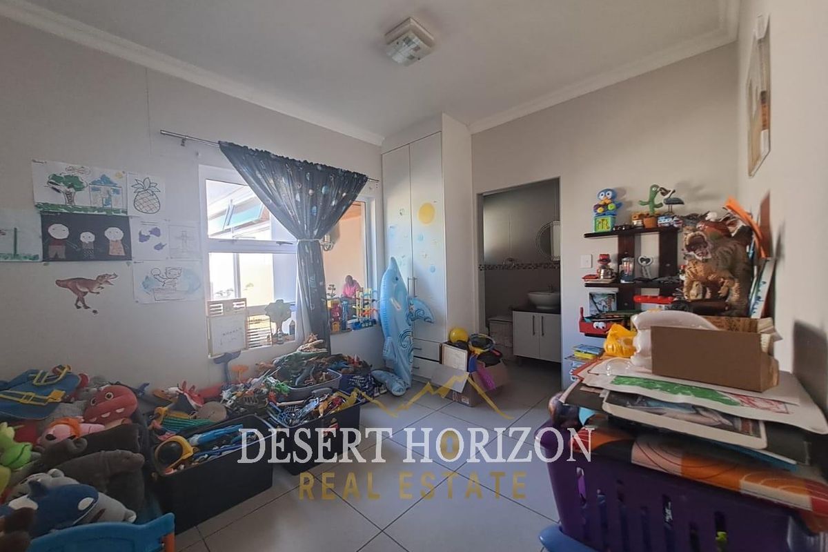 A bedroom featuring tiled flooring, a built-in wardrobe, and a window, currently utilized as a children's play area.