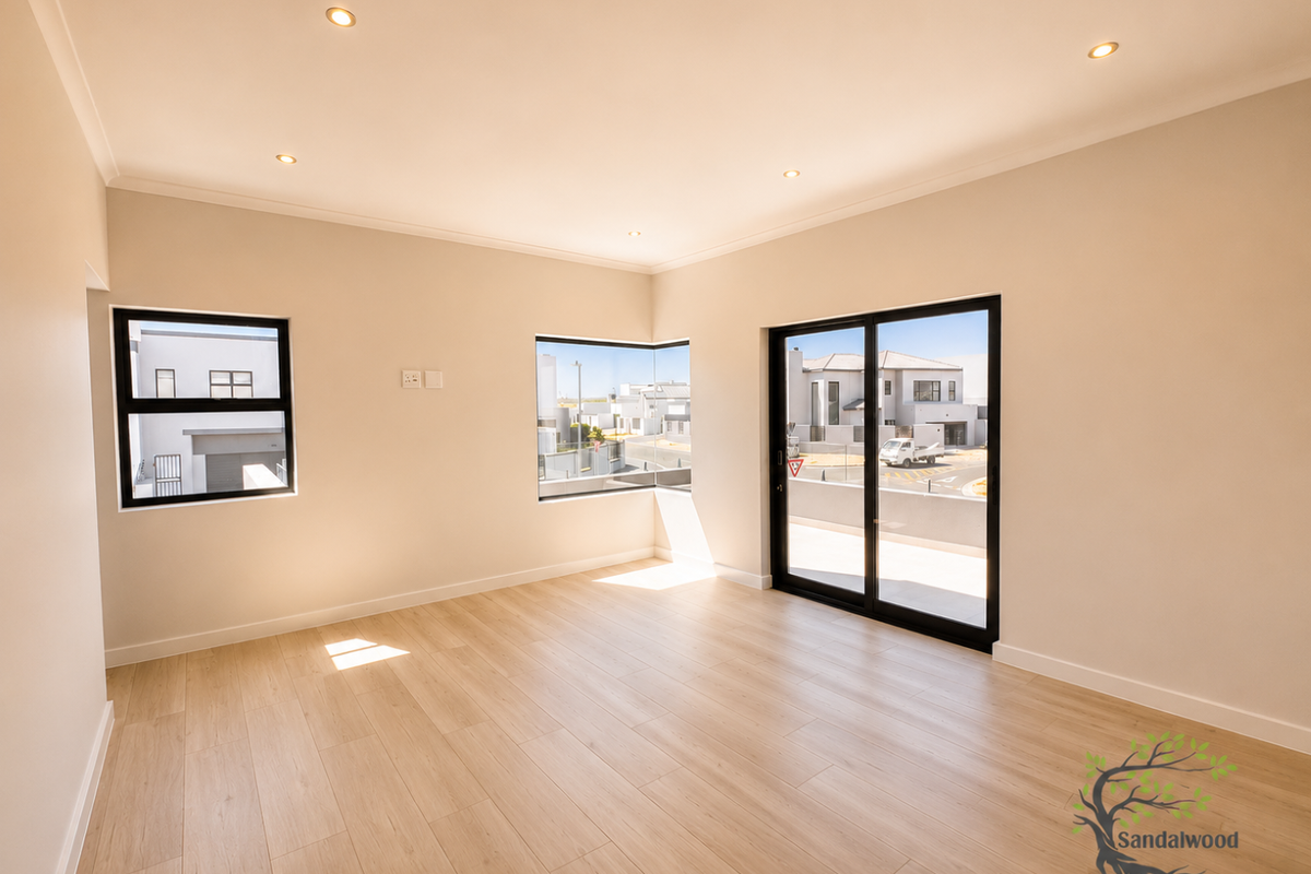 A bright, modern, and empty living room featuring light wood-look flooring, recessed downlighting, and large black-framed windows and sliding doors.