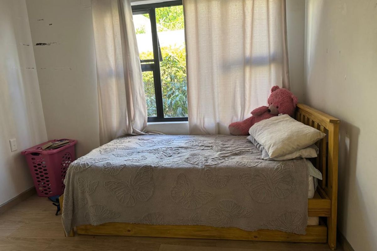 A bedroom featuring light wood-look flooring, a window with curtain tracks, and neutral wall finishes.