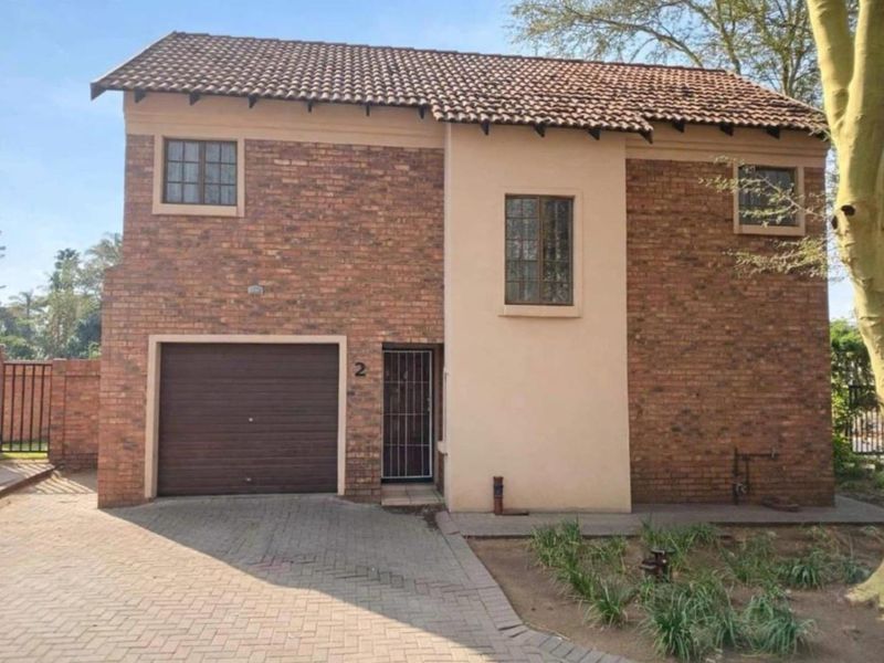 Front elevation of a two-story brick apartment unit featuring a single garage, paved driveway, and secure entrance.