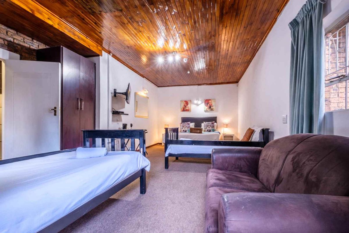 Spacious bedroom featuring a warm timber tongue and groove ceiling, exposed brick accents, and a built-in wardrobe for storage.