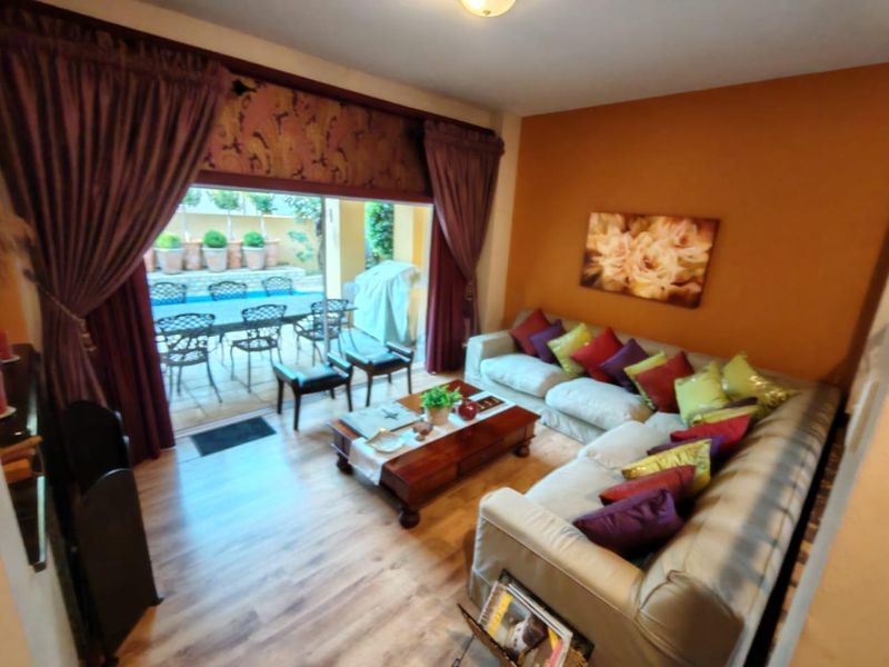 A comfortable living room featuring laminate flooring and a large sliding glass door that provides direct access to the outdoor patio and pool area.