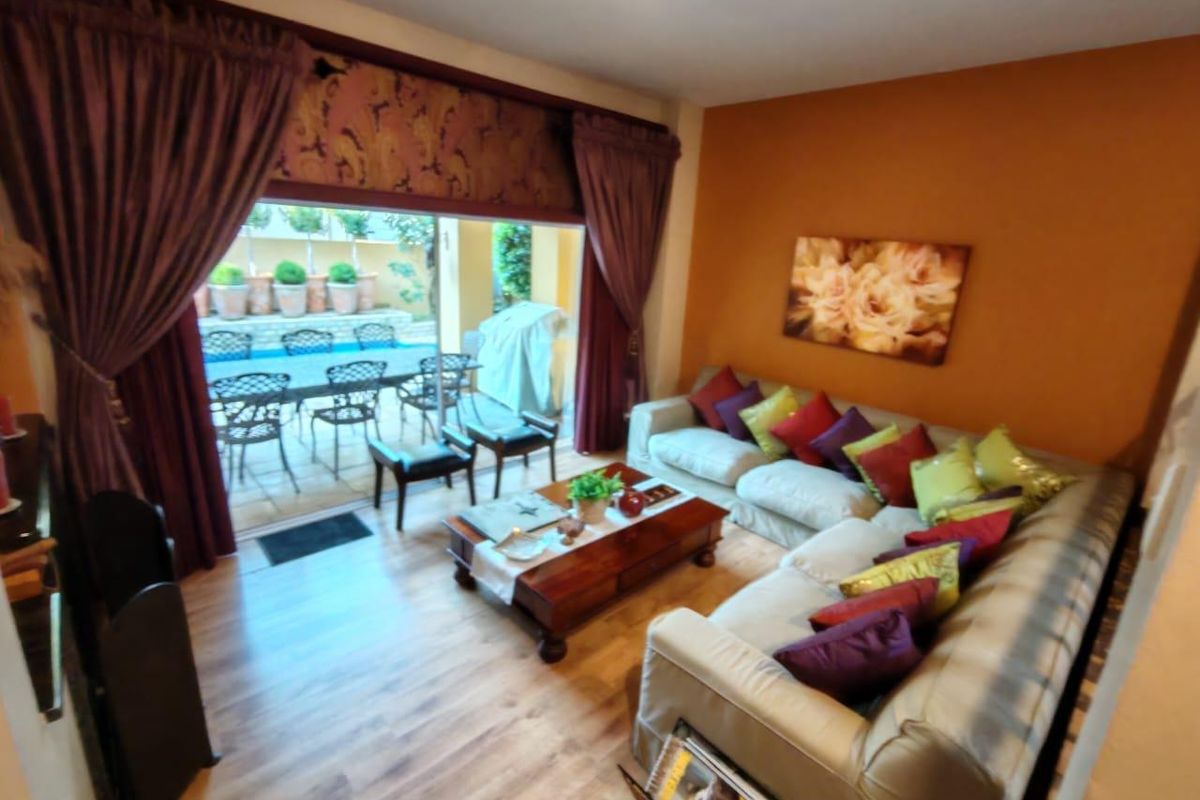 A comfortable living room featuring laminate flooring and a large sliding glass door that provides direct access to the outdoor patio and pool area.