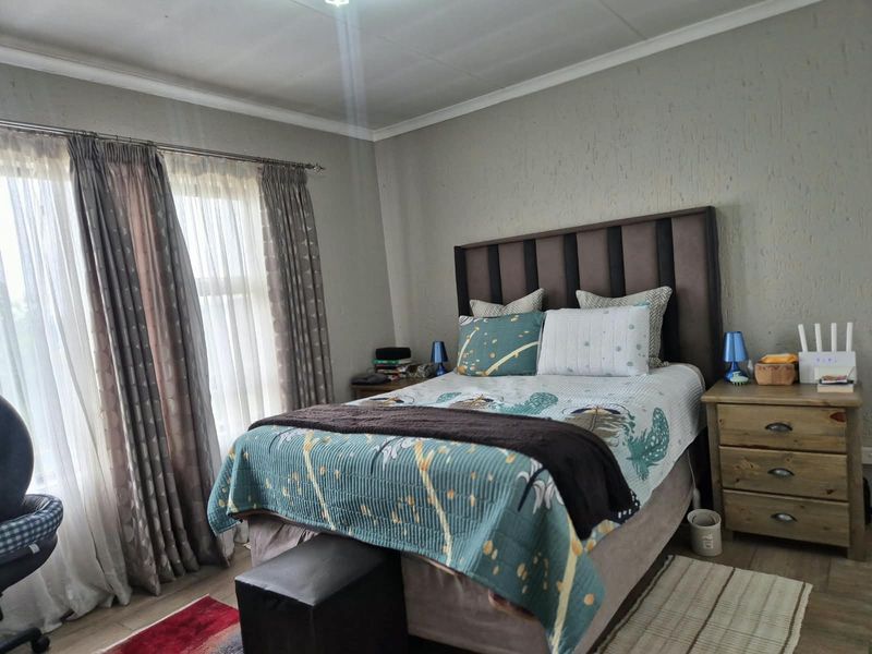 A well-lit bedroom featuring textured wall finishes, tiled flooring, and decorative cove cornicing, providing a comfortable and functional living space.
