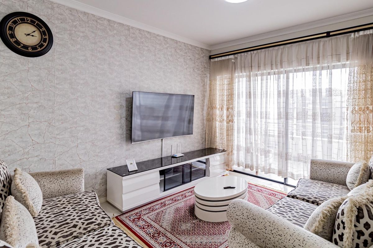 A well-maintained living room featuring textured wallpaper, cove molding, and a large sliding glass door providing access to the balcony.