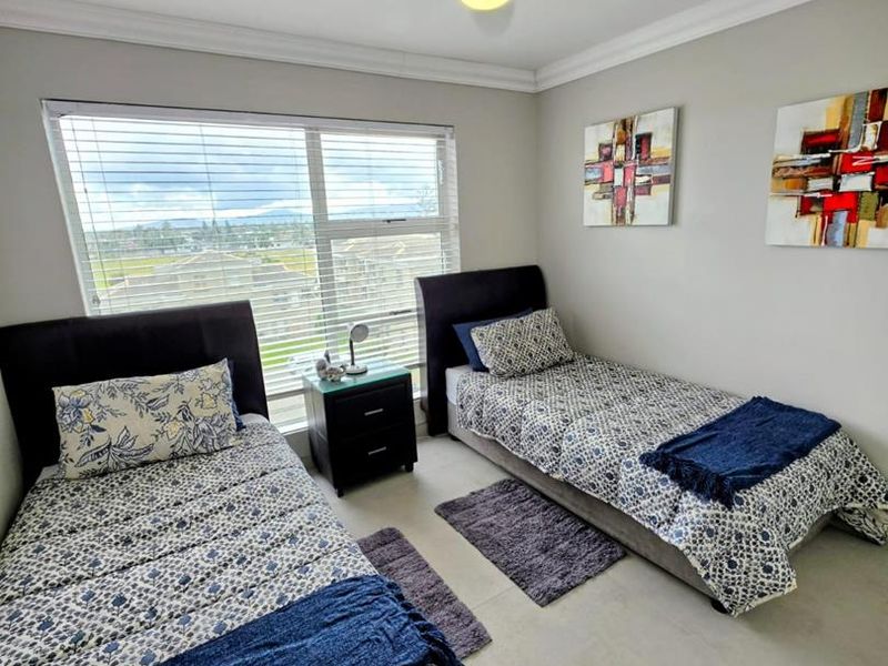 A well-maintained bedroom featuring tiled flooring, a ceiling fan, and large windows with venetian blinds, offering a bright and comfortable living space.