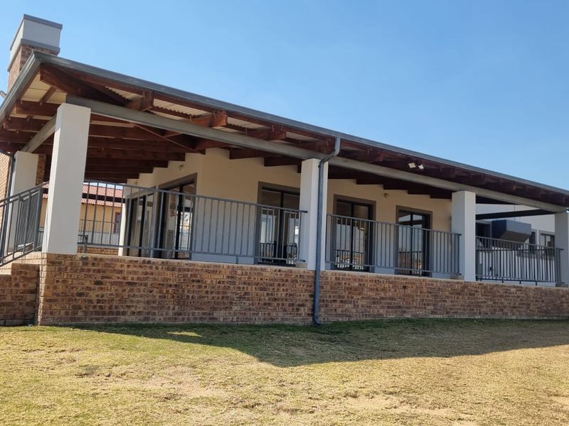 A spacious covered patio featuring exposed timber rafters, brick base detailing, and metal railings, providing an ideal outdoor entertainment area.