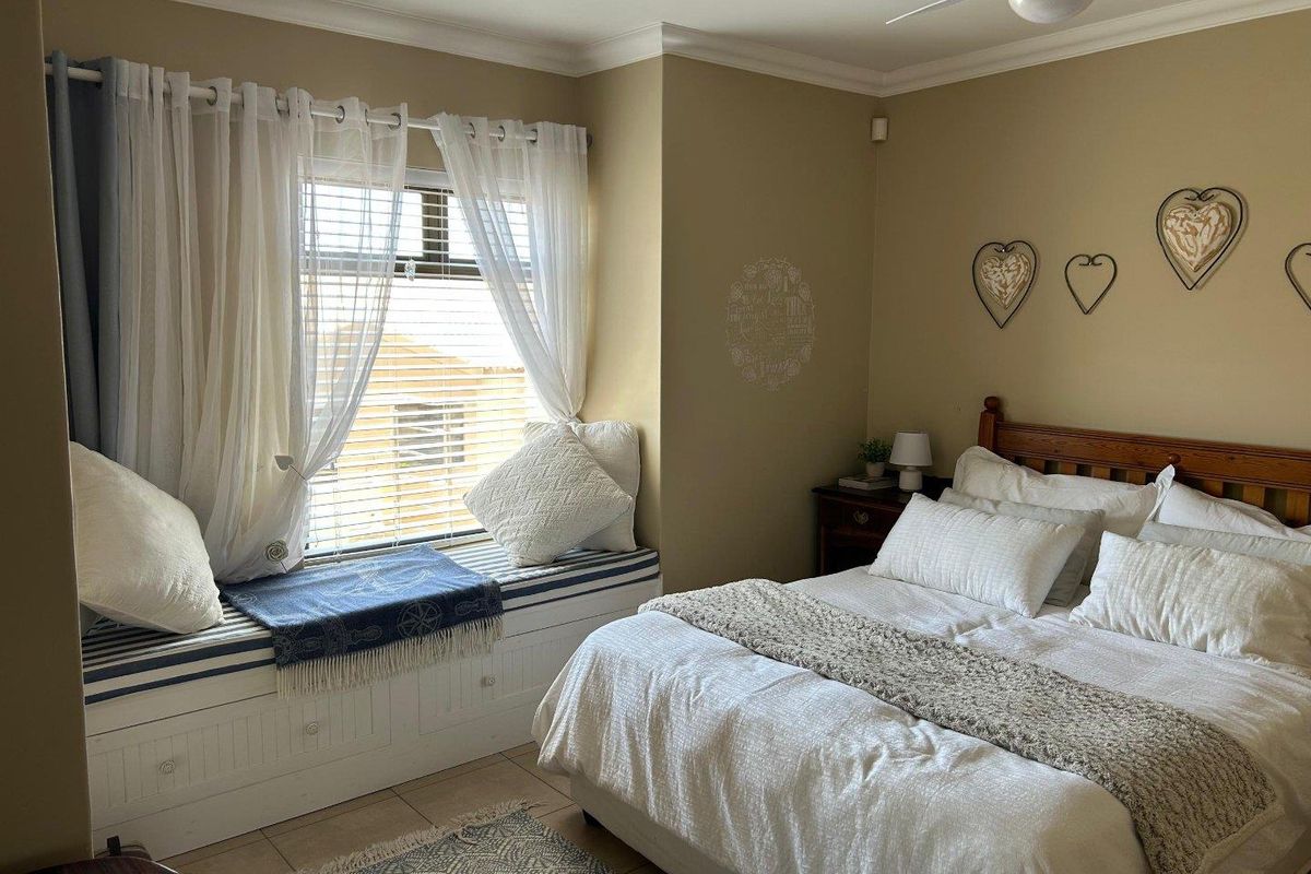 A cozy bedroom featuring a built-in window seat with storage, tiled flooring, and a ceiling fan.