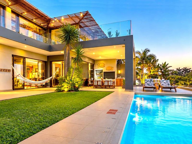 A luxurious rear exterior featuring a modern swimming pool, expansive covered patio with timber pergola, and seamless indoor-outdoor flow through large sliding glass doors.