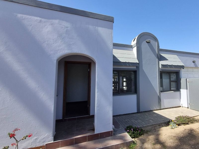 Front facade of the house featuring an arched entrance, paved walkway, and modern grey and white exterior paint finish.