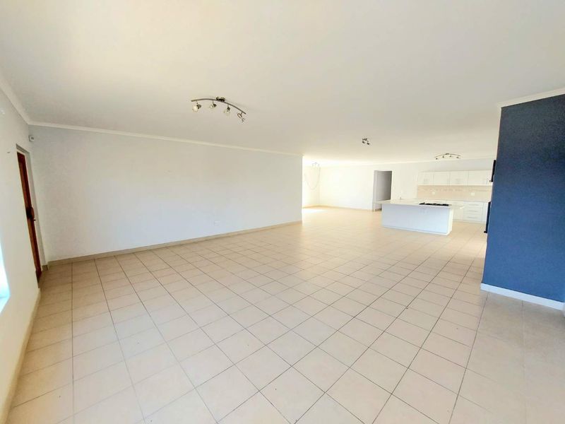 Spacious open-plan living area featuring tiled flooring and a functional kitchen with a central island and built-in cabinetry.