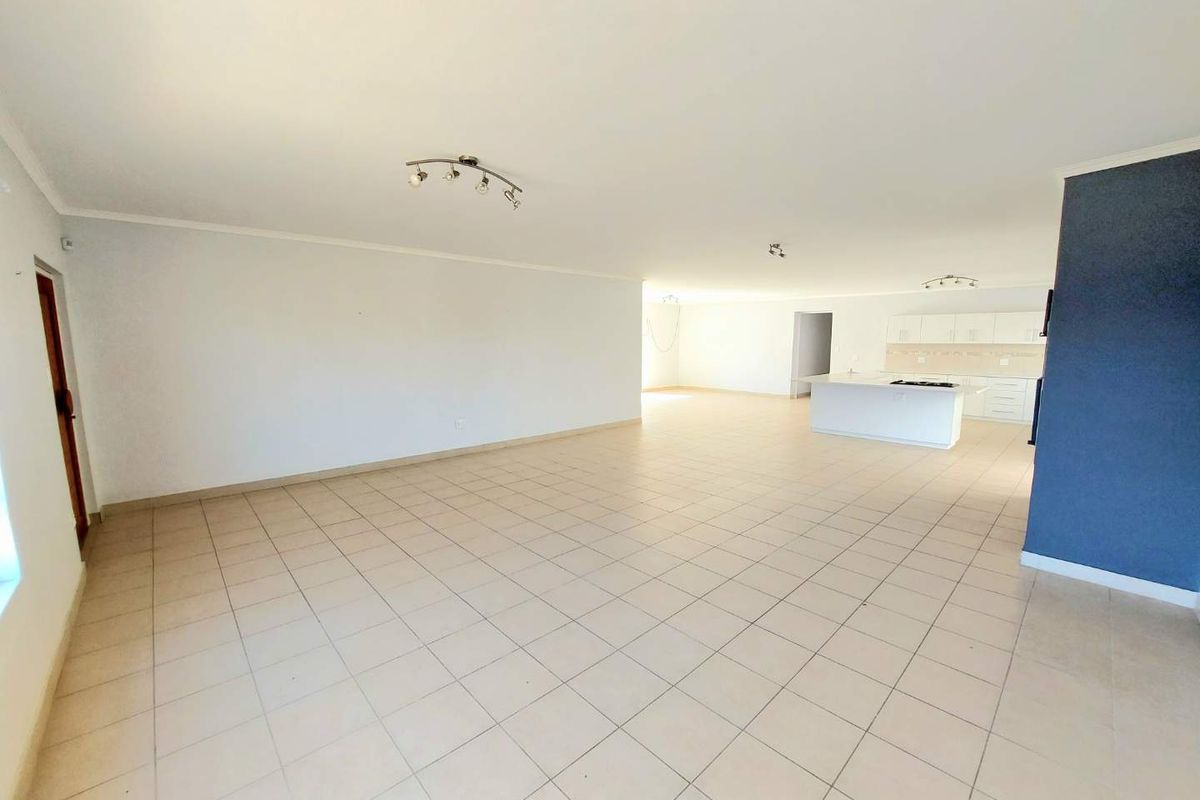 Spacious open-plan living area featuring tiled flooring and a functional kitchen with a central island and built-in cabinetry.