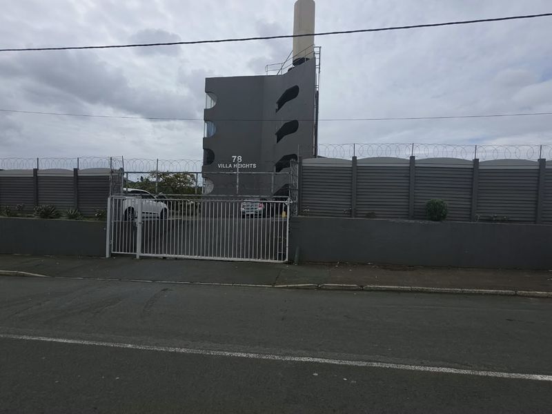 Street view of the Villa Heights apartment complex entrance, featuring secure perimeter fencing, razor wire, and a gated driveway access point.