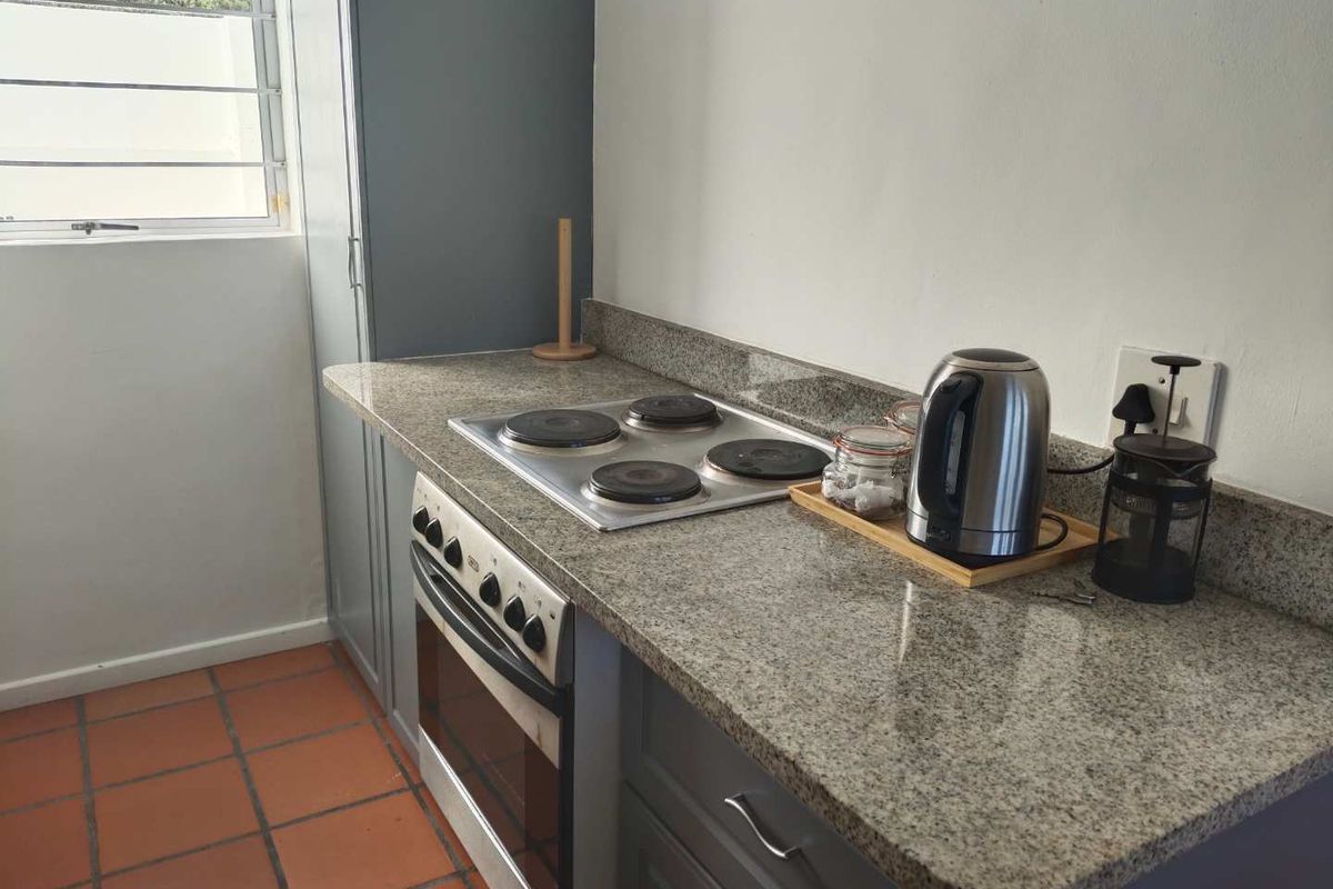 Compact kitchen featuring granite countertops, a built-in electric hob, and an under-counter oven with grey cabinetry.