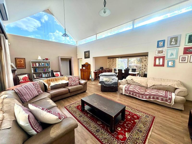 Spacious open-plan living and dining area featuring a high vaulted ceiling, abundant natural light from clerestory windows, and durable laminate flooring.