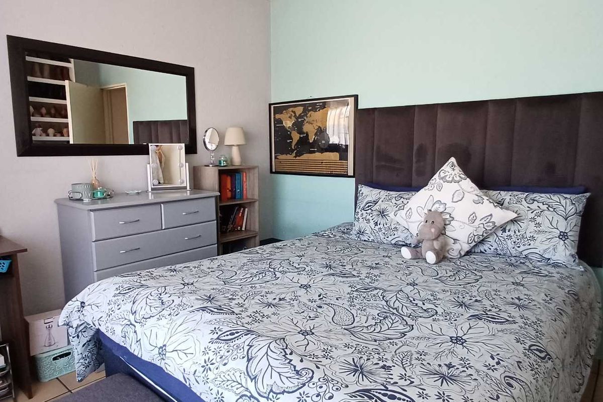 A well-maintained bedroom featuring a neutral color palette, tiled flooring, and a built-in headboard area, offering a comfortable and functional living space.