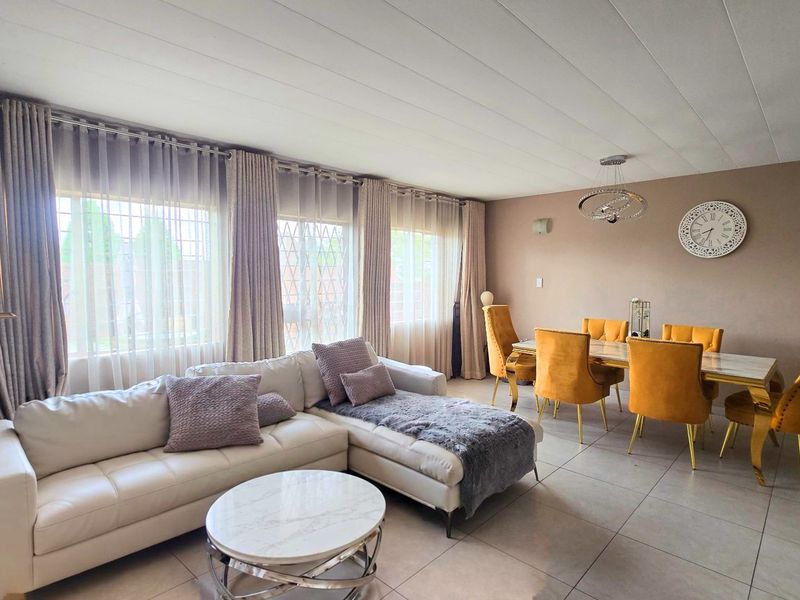 Spacious open-plan living and dining area featuring large windows with natural light, tiled flooring, and modern lighting fixtures.