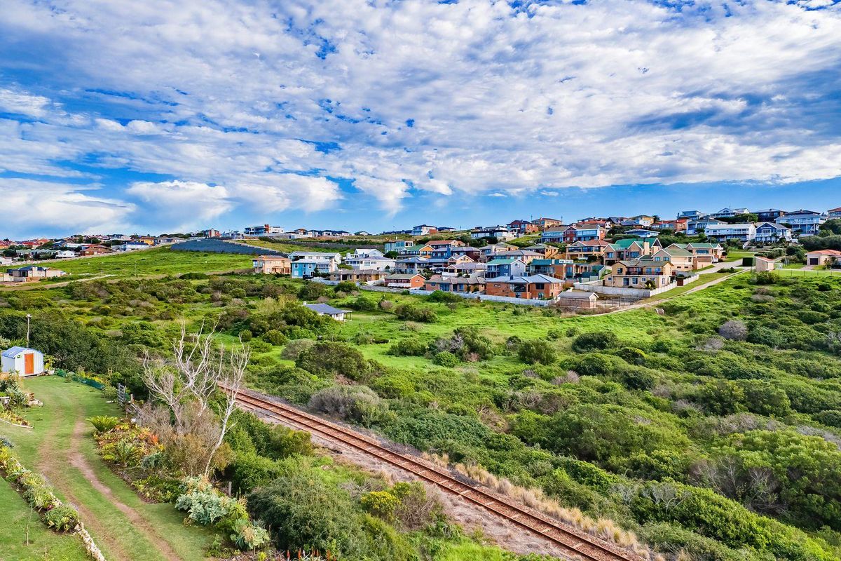 An aerial view of a residential neighborhood featuring natural vegetation and railway tracks running through the landscape.