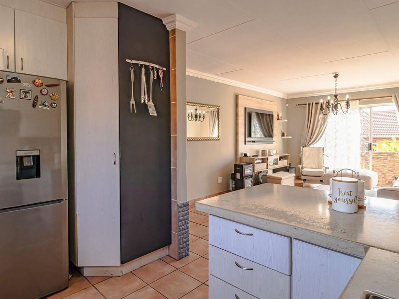Open-plan living area featuring a functional kitchen with stone countertops, tiled flooring, and seamless flow to the adjacent lounge and outdoor patio access.