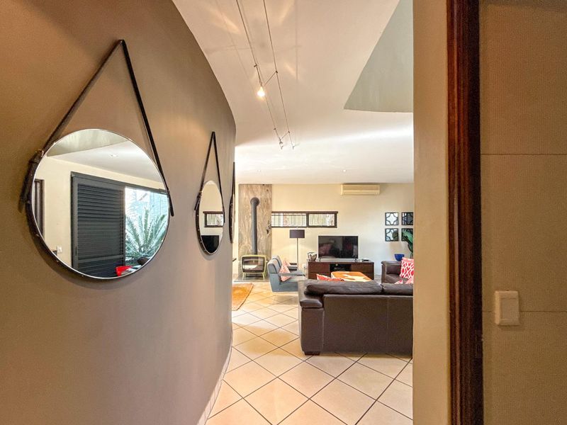 View from a hallway into a living room featuring ceramic tile flooring, a freestanding fireplace, and a split-system air conditioner.