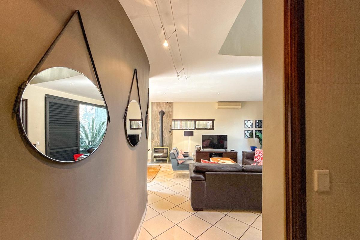View from a hallway into a living room featuring ceramic tile flooring, a freestanding fireplace, and a split-system air conditioner.