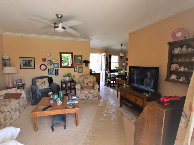 Open plan living and dining area featuring crown molding, a ceiling fan, and a mix of carpeted and tiled flooring.