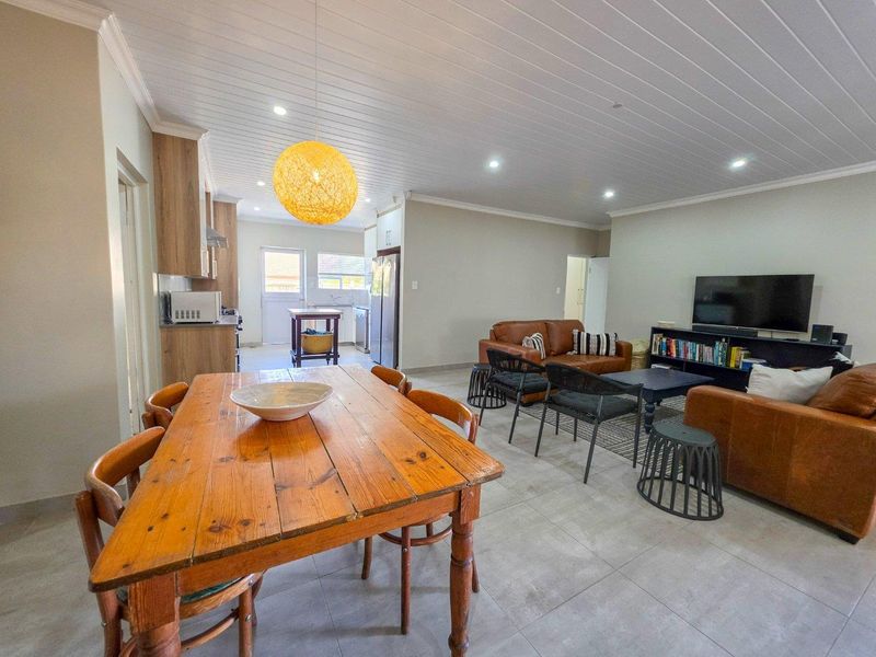 Spacious open-plan living area featuring tiled floors, a tongue and groove ceiling with recessed lighting, and a functional kitchen with built-in cabinetry.