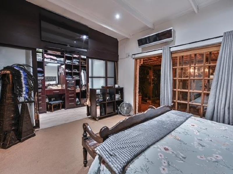 Spacious bedroom featuring built-in cabinetry, exposed ceiling beams, and sliding glass doors providing access to an outdoor area.