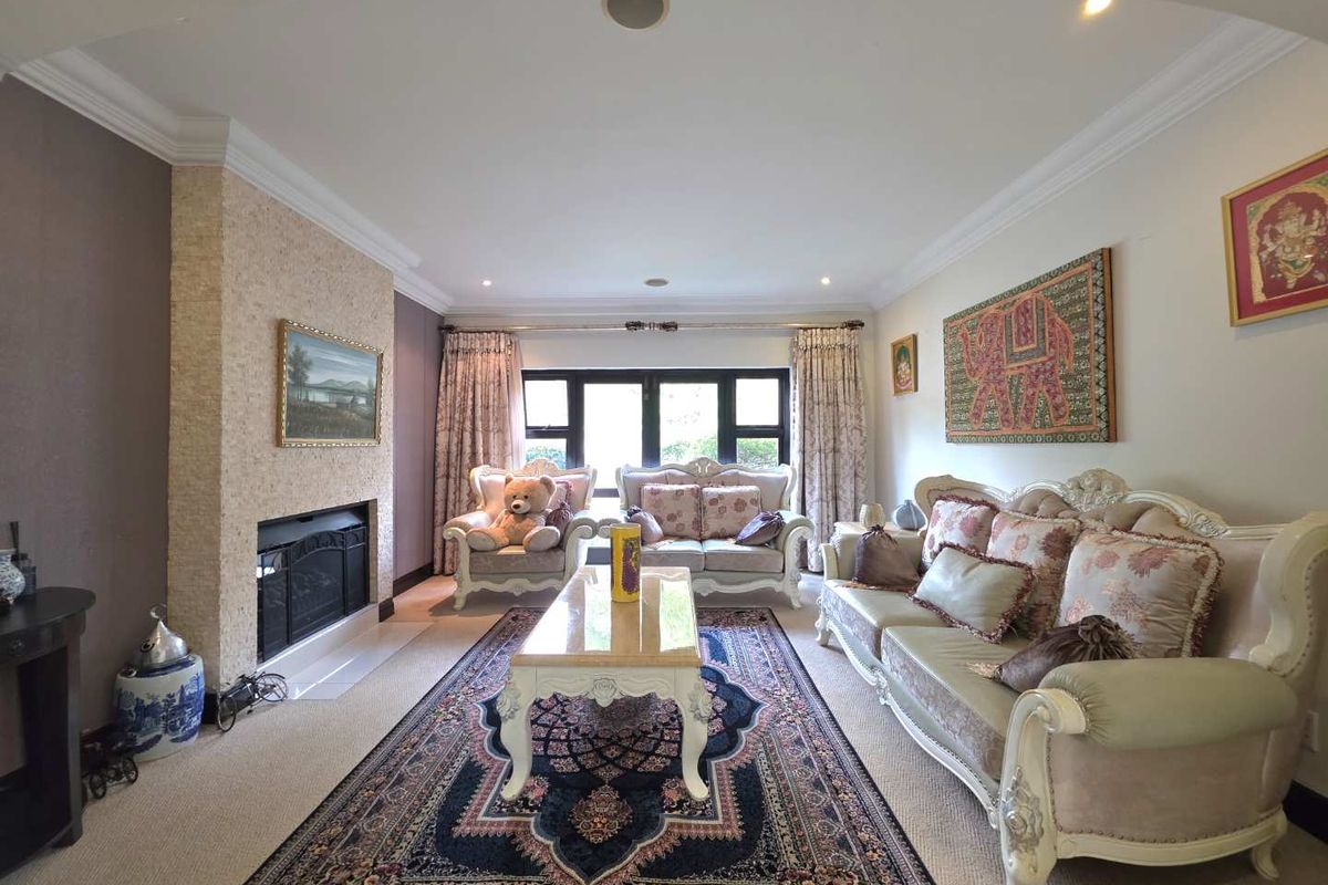 Spacious living room featuring a built-in fireplace with textured stone surround, recessed ceiling lighting, and large windows providing natural light.
