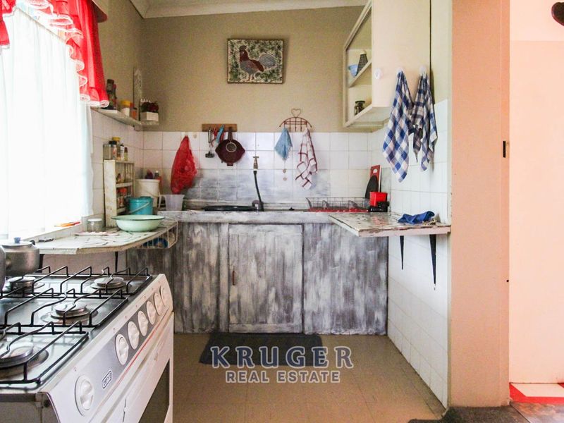 A dated kitchen featuring a gas stove, tiled splashback, and built-in cabinetry, offering potential for a modern renovation.